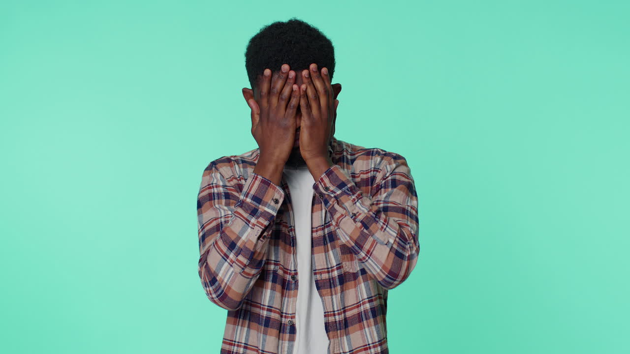 Scared man closing eyes with hand showing stop gesture, confused shy scared to watch, freaked out