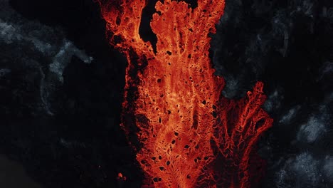 gran río que fluye de lava roja fundida en un entorno volcánico accidentado, de arriba hacia abajo
