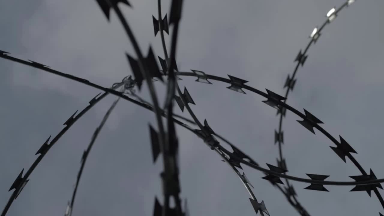 Metal razor wire protection against gray sky close up