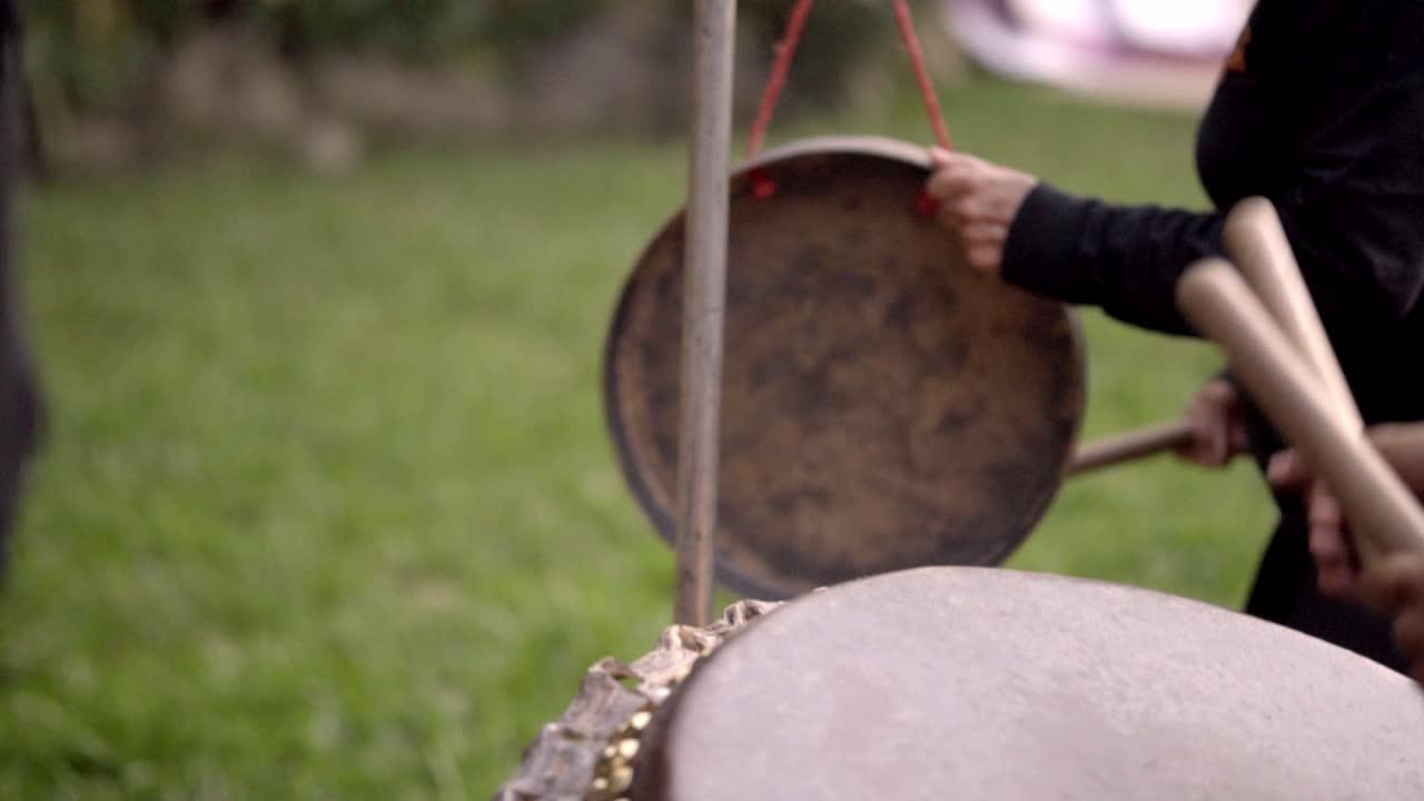 Close-up of people playing traditional drums outdoors, rhythmic and lively
