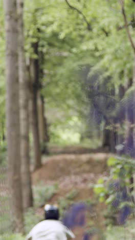 Vertical-Video-Of-Man-On-Mountain-Bike-Making-Mid-Air-Jump-On-Dirt-Trail-Through-Woodland-2