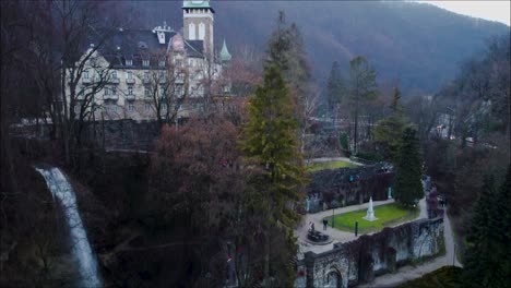 Drone-shot-in-vertical-direction-upwards-of-a-hungarian-castle-with-a-waterfall