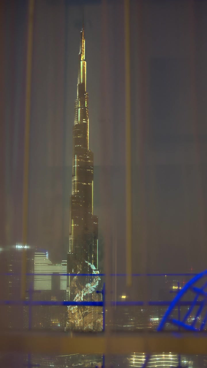 Burj Khalifa Illuminato di Notte Visto Attraverso le Tende della Finestra