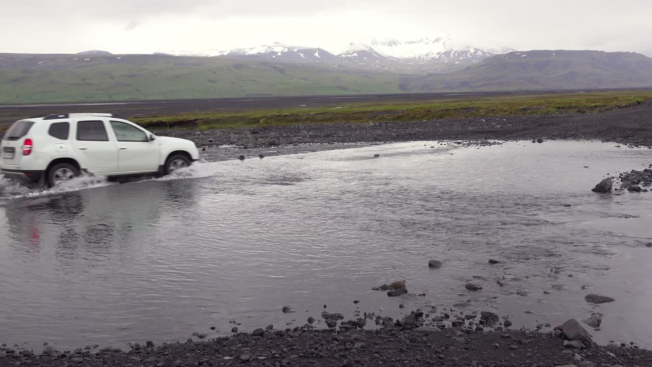 A SUV drives through a river in the remote highlands of Iceland