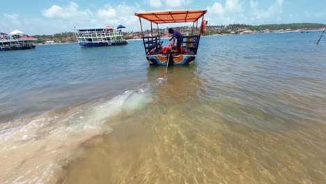 Tilt-up-slow-motion-action-camera-shot-from-of-a-small-tourist-boat-sailing-away-from-the-tropical-Restinga-beach-near-Barra-do-Cunhaú-in-Rio-Grande-do-Norte,-Brazil-with-large-boats-passing-by