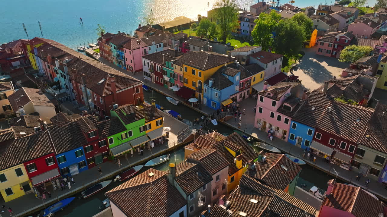 Aerial drone view of boats on the sides of a canal near the colourful houses of Burano Island, Italy