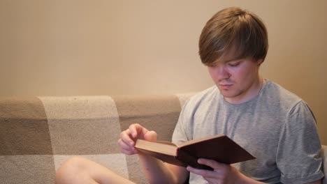 man reading a book on a couch