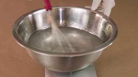 mixing chemical ingredients in a bowl on a weighing machine