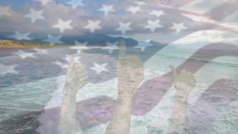 Digital-composition-of-waving-us-flag-over-hands-showing-thumbs-up-against-aerial-view-of-the-beach