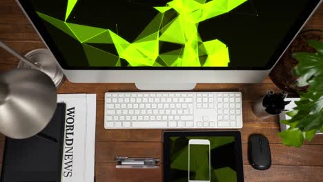 Animation-of-technological-devices-with-green-shapes-on-screen-on-wooden-desk