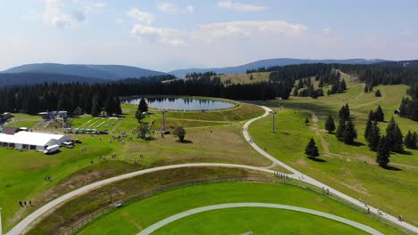 trails in rogla sports resort slovenia during springtime passing around a small lake near a soccer field, aerial flyover shot