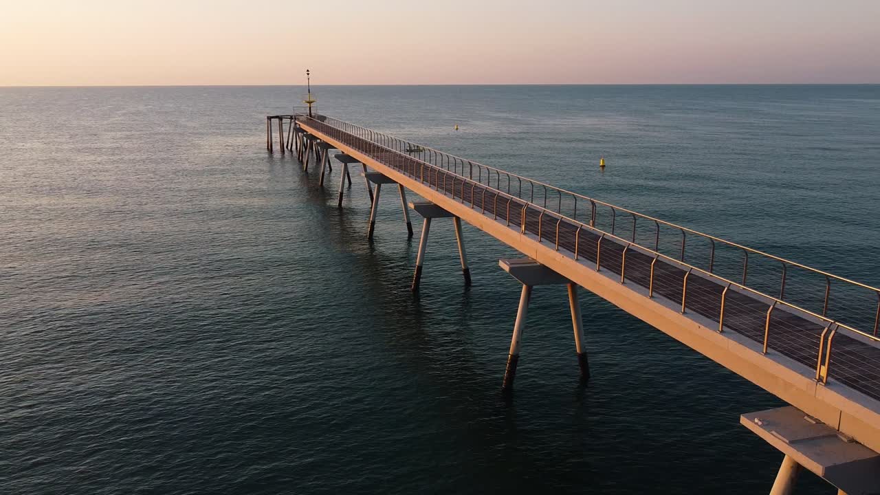 increíble toma de un embarcadero, volando alrededor de su estructura creando una perspectiva tridimensional de su arquitectura, mientras un suave viento sopla sobre las tranquilas aguas durante el crepúsculo