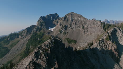 Aerial-footage-rotating-around-a-granite-peak-of-a-mountain-in-the-morning-haze-in-the-Cascade-Mountains-in-Washington