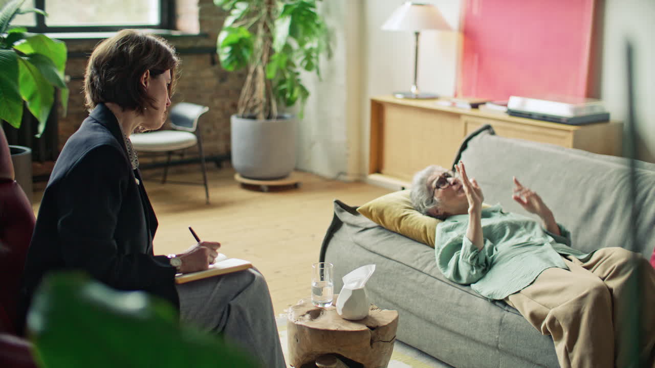 Elderly Woman Lying on Sofa and Sharing Feelings during Counseling Session