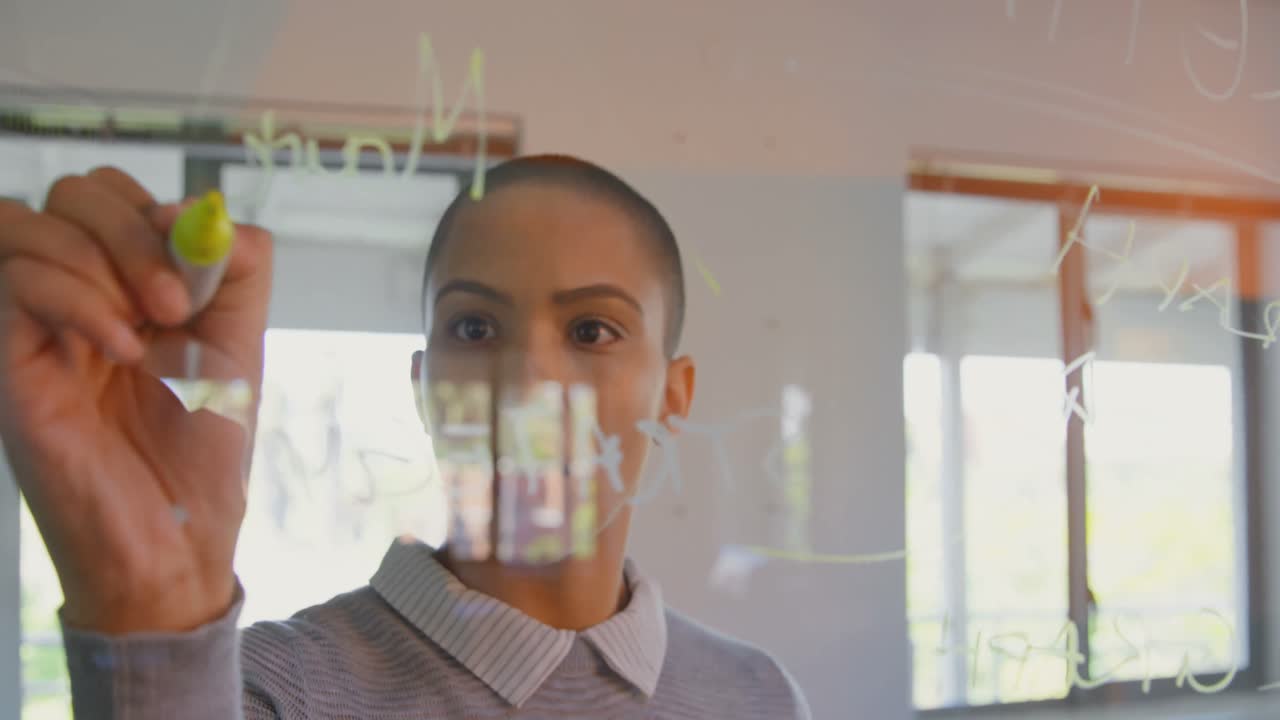 joven ejecutiva caucásica escribiendo en un tablero de vidrio en una oficina moderna 4k