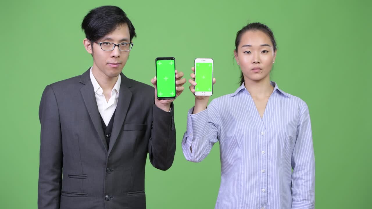 Young Asian business couple showing phone together