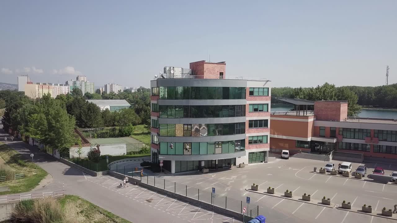 alejarse rápidamente de los trabajadores escaladores de gran altitud que limpian las ventanas de la oficina para revelar el negocio completo en el paisaje urbano del centro de la ciudad junto al río