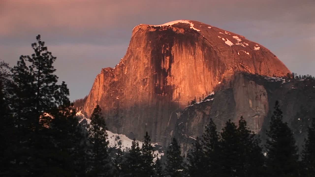 Close-up médio do Half Dome em Yosemite, brilhantemente iluminado pelo sol da hora dourada.