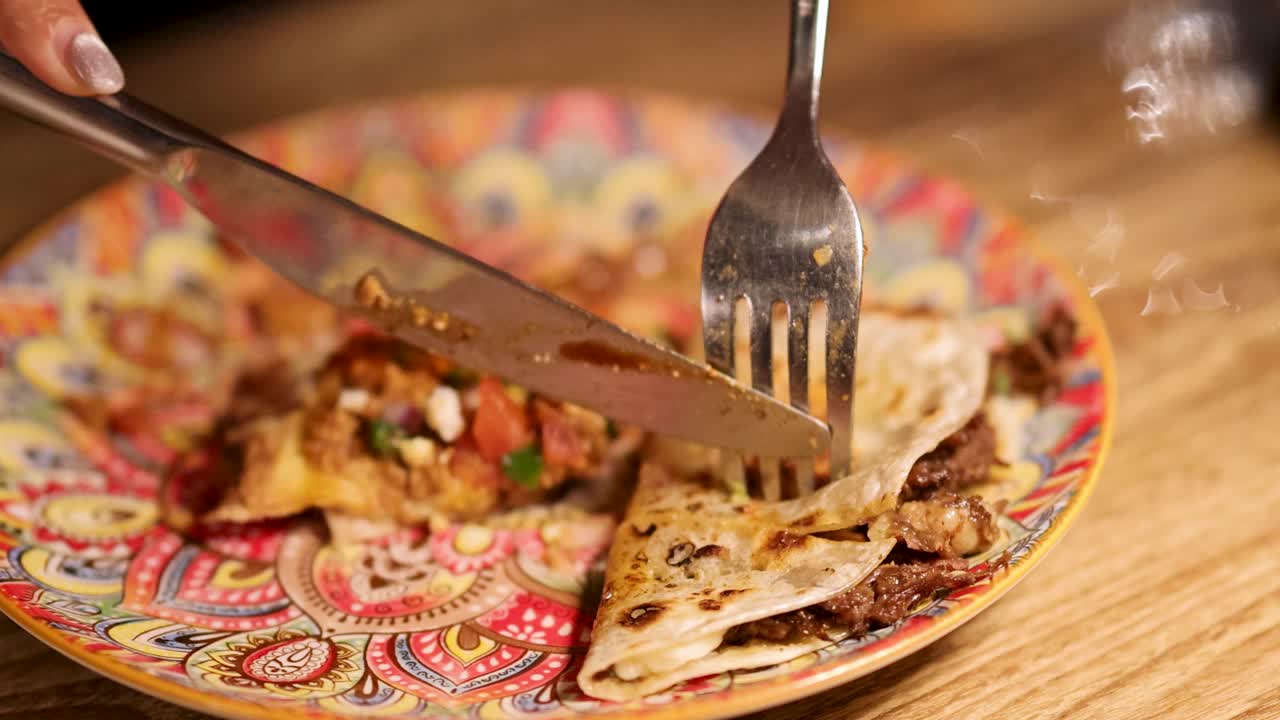 Close-up of grilled meat fajitas being sliced on a vibrant plate. Warm lighting enhances the appetizing presentation
