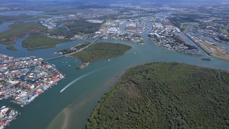 vista aérea de una lancha rápida navegando a lo largo del suburbio costero de paradise point y la isla de coomera en qld, australia