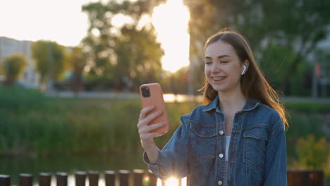 young woman having a video call in a park at sunset