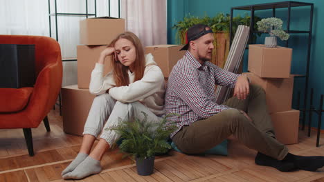 sad married couple on floor near cardboard boxes, divorce, long relocation, bankruptcy, bank debt