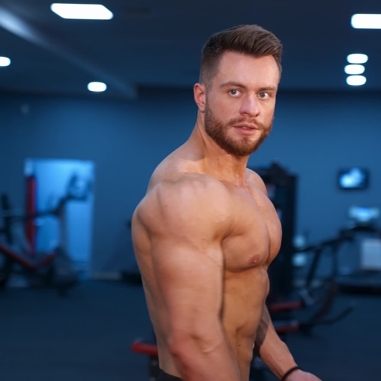 Strong athletic man in sports center. Muscular bodybuilder showing his naked torso in gym. Handsome shirtless sportsman with athletic body.