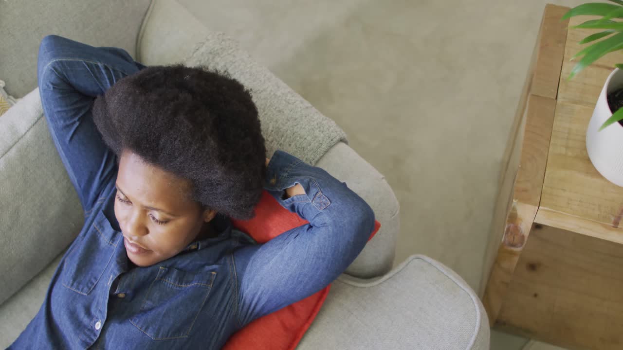 Happy african american woman laying on sofa with eyes closed