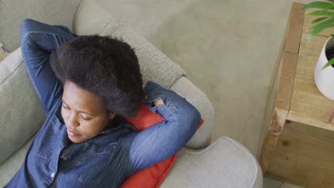 happy african american woman laying on sofa with eyes closed