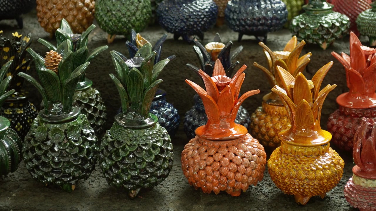 Assorted colorful pineapple shaped crafts arranged in rows at artisan market stall