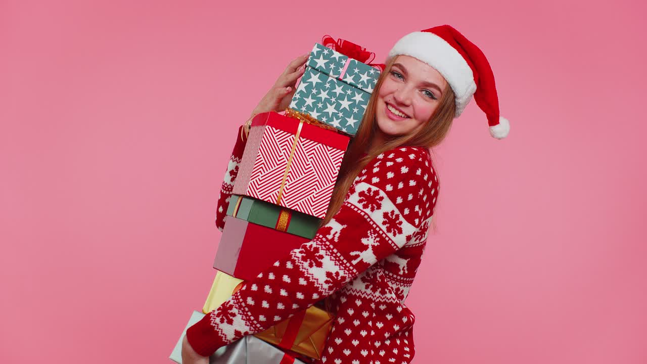 Woman in christmas red sweater santa hat smiling holding many gift boxes new year presents shopping