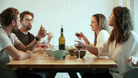 joyful friends talking while drinking red wine