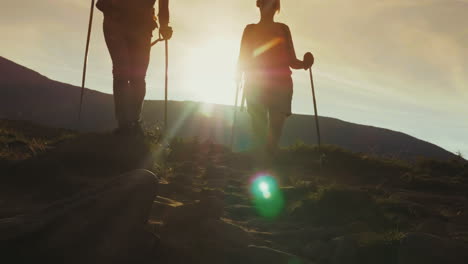 amanecer del sol en las montañas las siluetas de dos viajeros se encuentran descendiendo a lo largo de un camino de montaña 4k