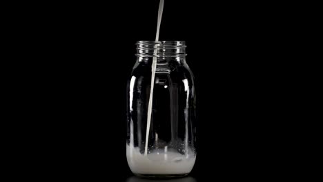 la leche llena gradualmente los frascos de vidrio con pajitas