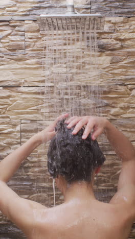 video vertical de una mujer biracial tomando una ducha en el baño