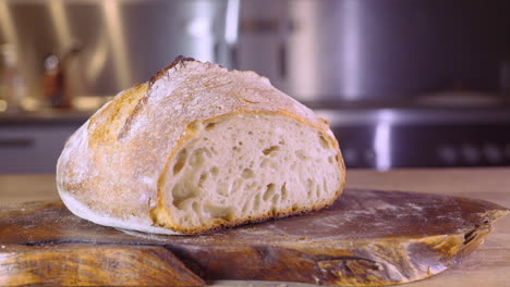 Cortar-Pan-De-Masa-Fermentada-En-Una-Tabla-De-Madera-En-La-Cocina---Pan-Shot,-Enfoque-Selectivo