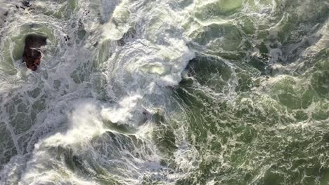 Cinematic-Cenital-Static-Shot-of-Rough-Ocean-Waves-Hitting-Rocks-During-Sunset-at-Cape-Town's-Camps-Bay-Beach