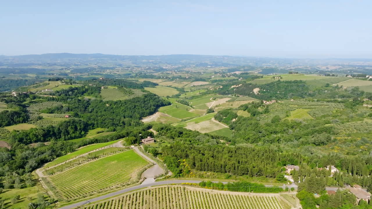 Aerial view tilting backwards over fields, forest and rural nature in Tuscany