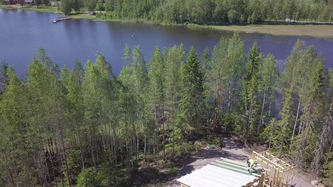 Construction worker walking on roof of a cabin cottage, aerial shot