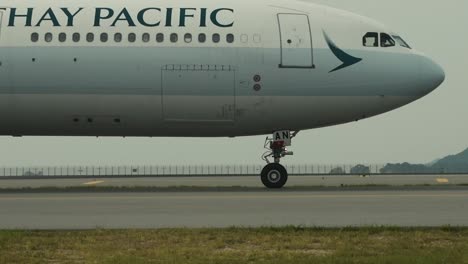close up of a cathay pacific airplane slowly passing by on the runway