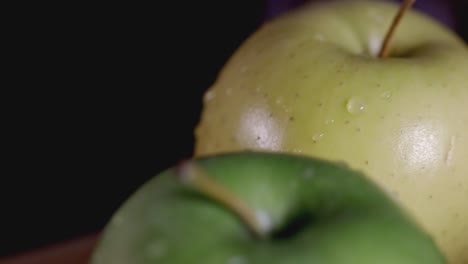 the yellow and green fresh apple rotating on the wooden table - closeup shot