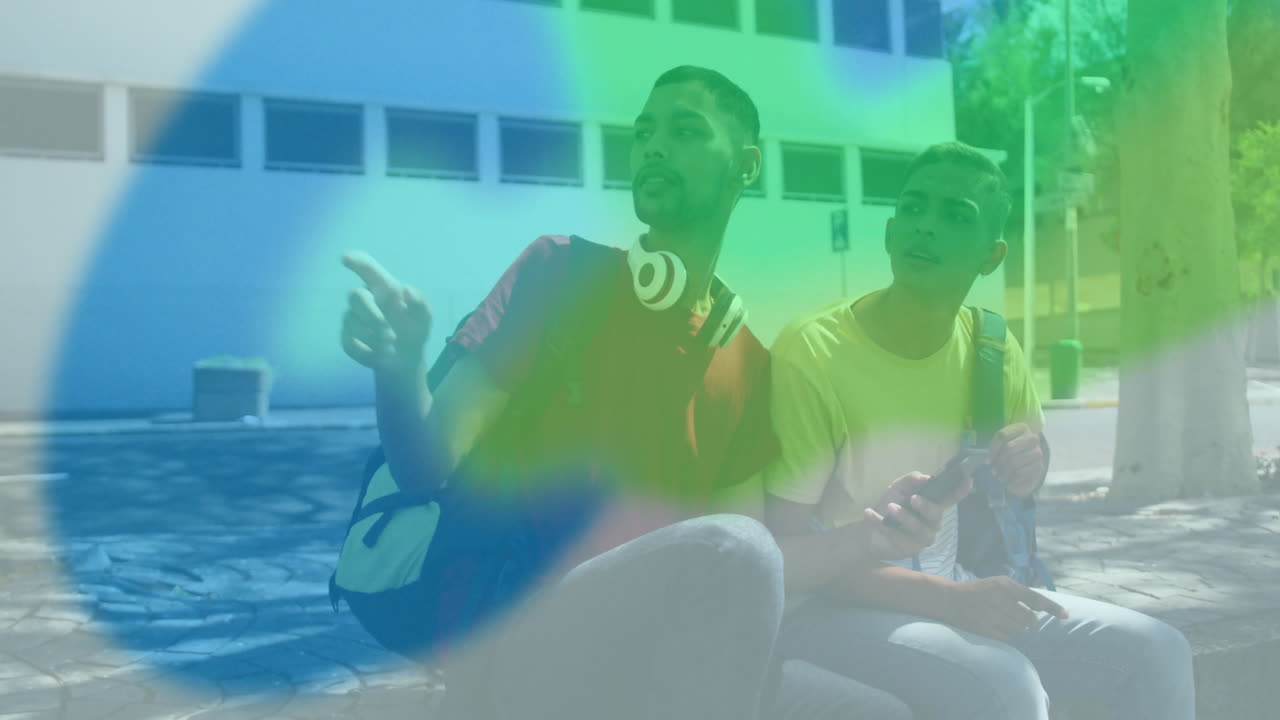 Sitting outdoors, two people with colorful light animation overlaying them