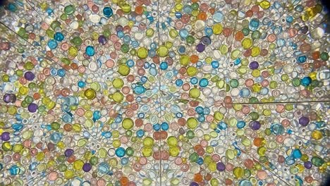 a colorful mosaic of reflections and patterns: captivating display of vibrant glass beads and shapes showcasing intricate details of a kaleidoscope effect