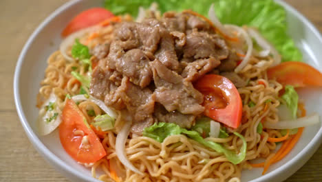 ensalada picante de fideos instantáneos con carne de cerdo en un plato blanco - estilo de comida asiática