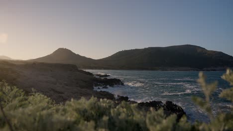 Calm-and-beautiful-coast-shore-line-scenery-with-crashing-waves-and-clear-water-at-golden-hour-sunset