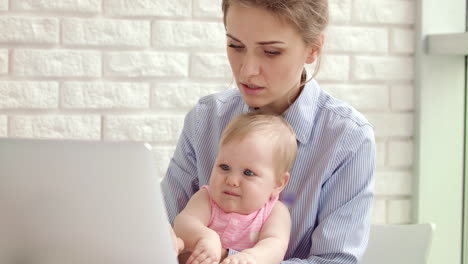 Concentrated-woman-with-baby-working-on-laptop.-Business-woman-working