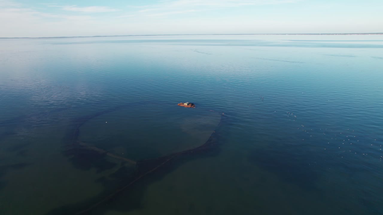 거대한 수중 물체, 공중 드론 샷으로 호수 한가운데 있는 조류 관찰 스테이션 주위를 날아다니는 새들