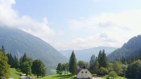 Drone-shot-of-a-white-cabin-and-reveal-mountain-valley-behind-it