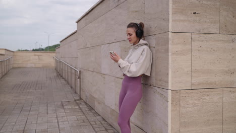 woman outdoors using phone while wearing headphones