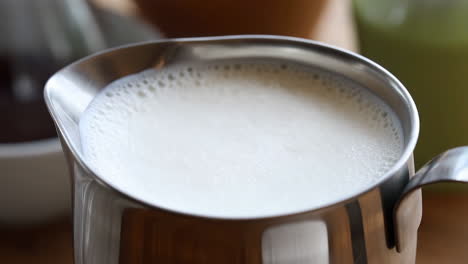 close-up of frothed milk in a stainless steel pitcher